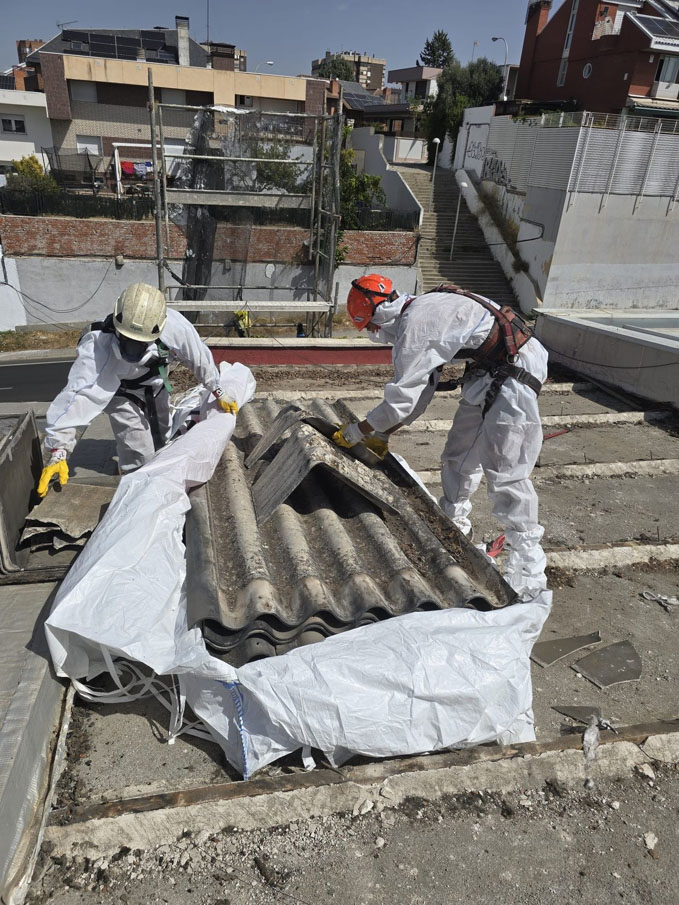 Operarios desmontando una placa de fibrocemento con amianto y depositándola sobre el embalaje
