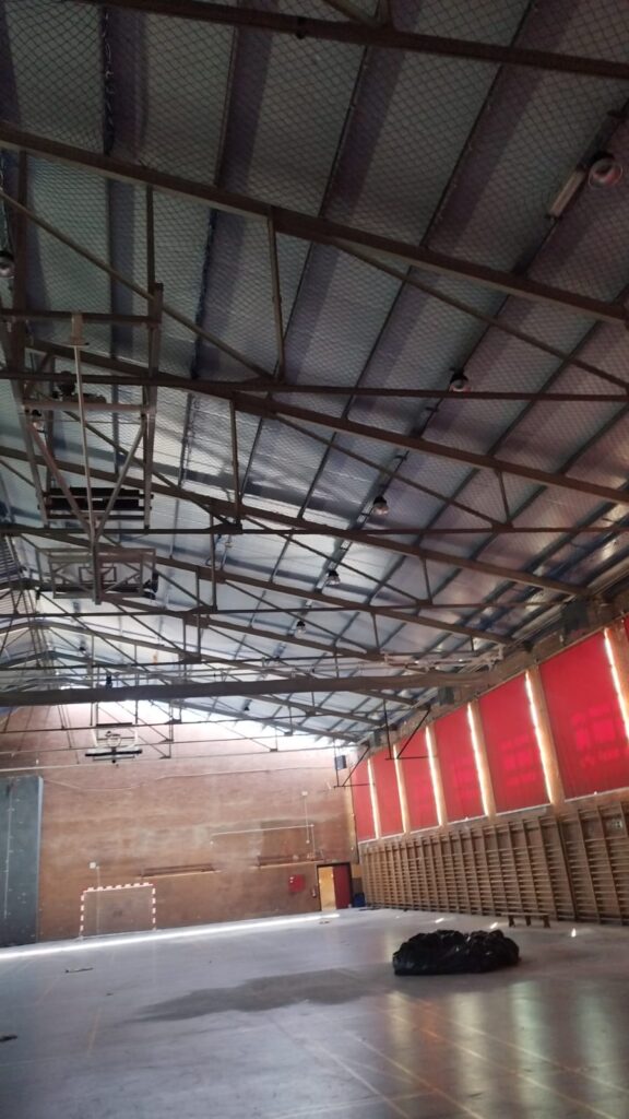 Polideportivo del IES San Fernando antes de retirar la cubierta de fibrocemento, con redes bajo las cerchas
